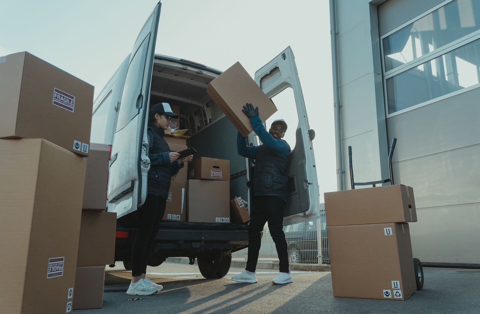 Zwei Mitarbeitende verladen Kartons an einem Transporter