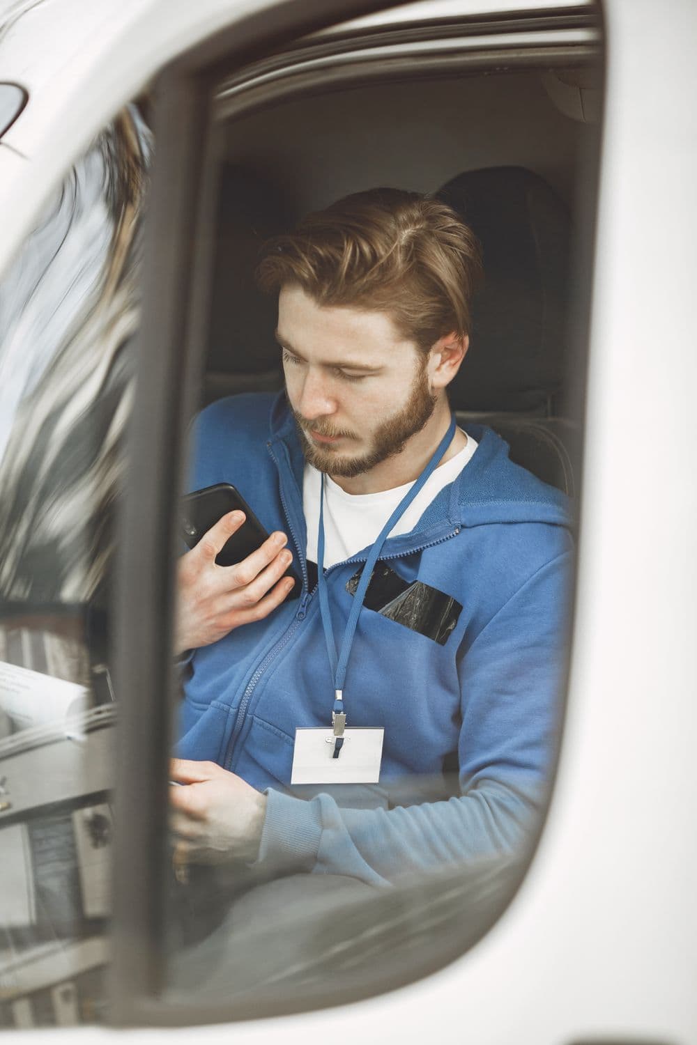 Fahrer sitzt im Transporter und nutzt die Fahrer-App auf dem Smartphone