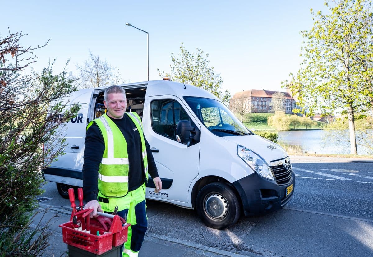 Handwerker mit Werkzeugkiste vor seinem Transporter