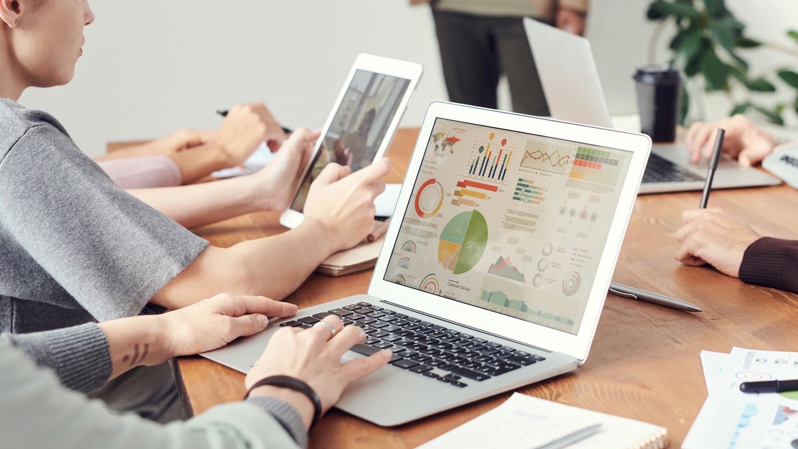 Team vergleicht am Besprechungstisch Kriterienlisten für eine Fuhrparksoftware auf Papier und Bildschirm